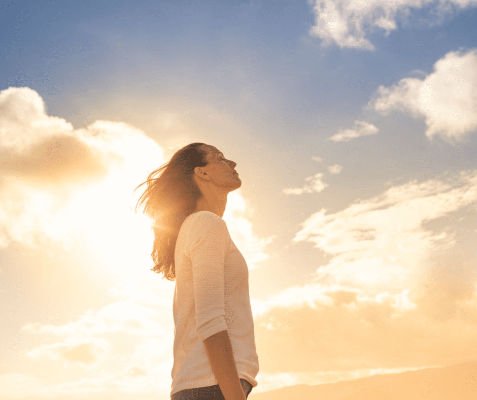 Woman enjoying sunlight with closed eyes, feeling peaceful and free