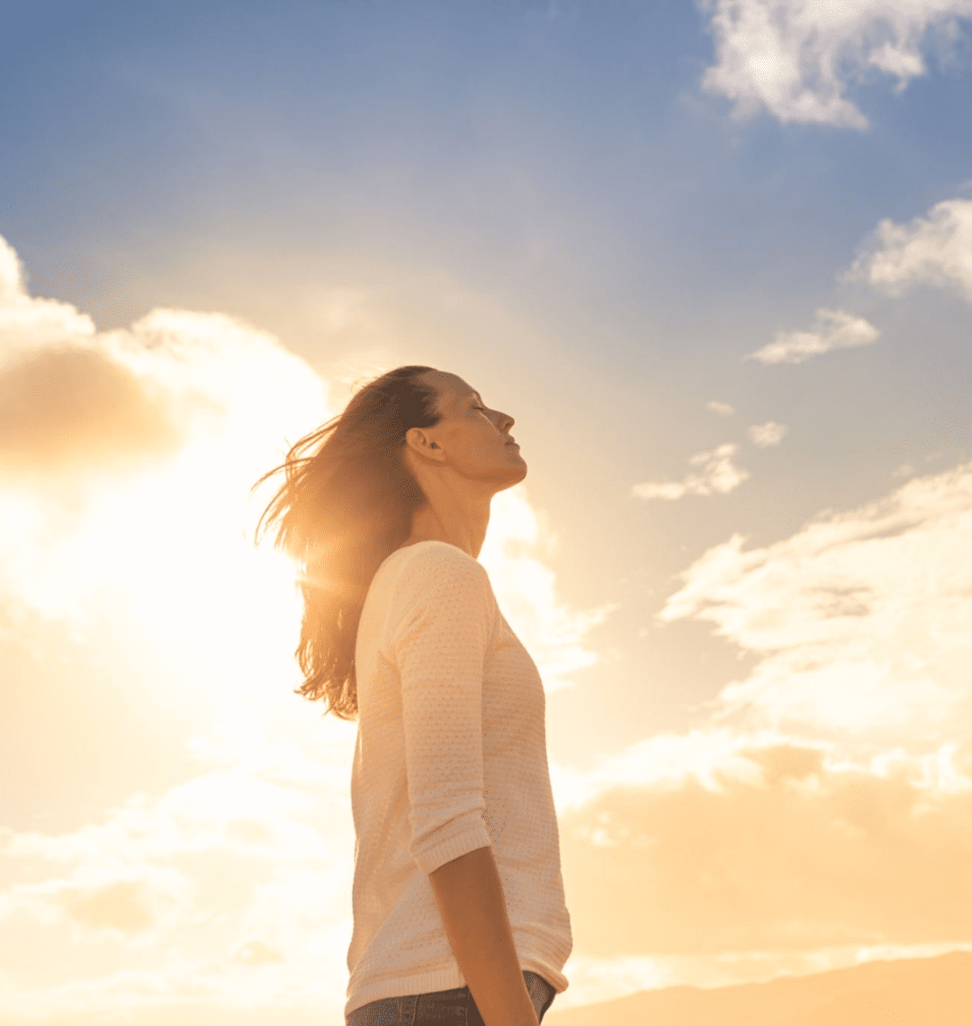 Woman enjoying sunlight with closed eyes, feeling peaceful and free