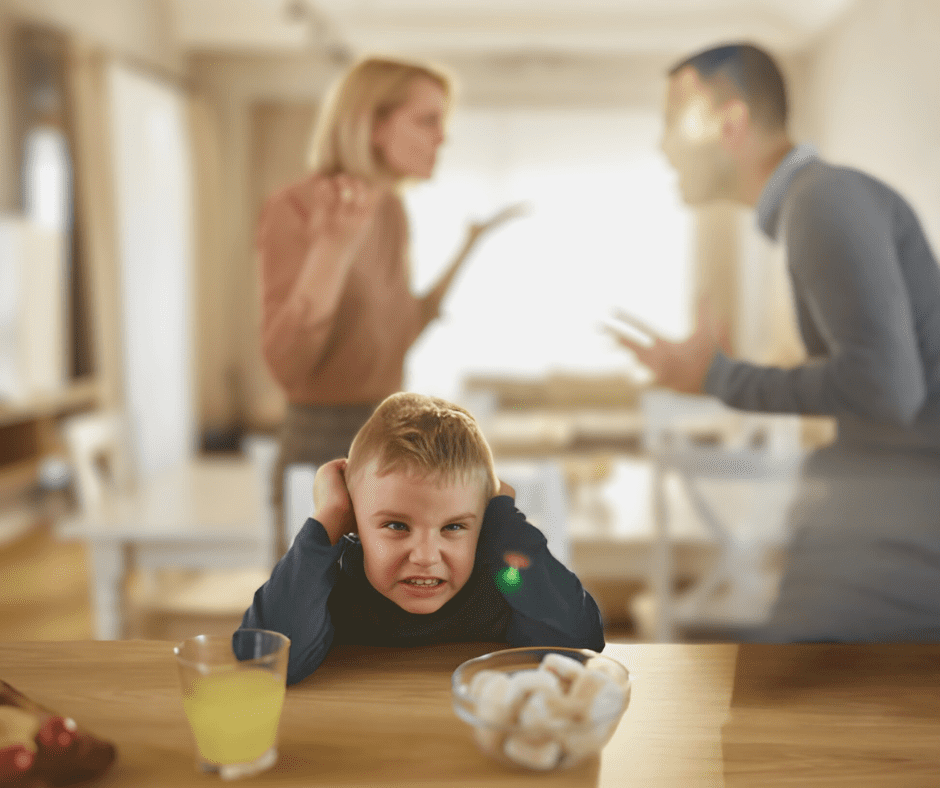 A distressed young boy covers his ears while his parents argue in the background. The mother gestures emotionally, while the father responds intensely, both unaware of their child’s discomfort