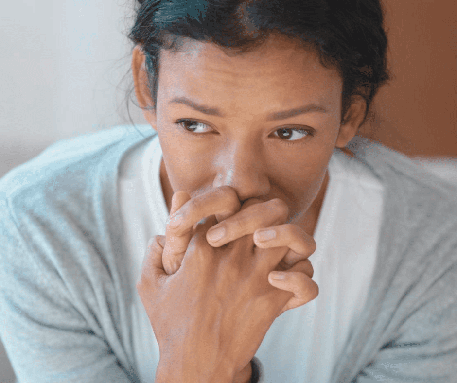 Anxious Woman Deep in Thought Close-up of a worried woman with clasped hands, reflecting anxiety or emotional stress indoors