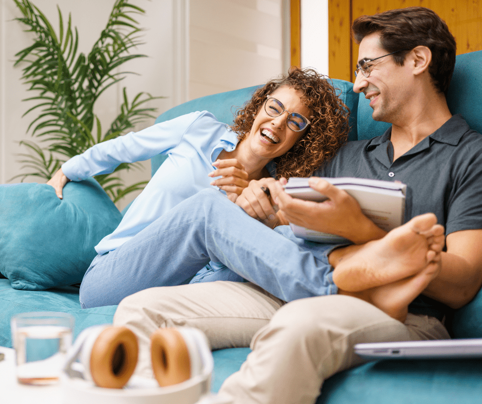 Smiling couple relaxing on a couch, reminiscing about their journey from single life to marriage