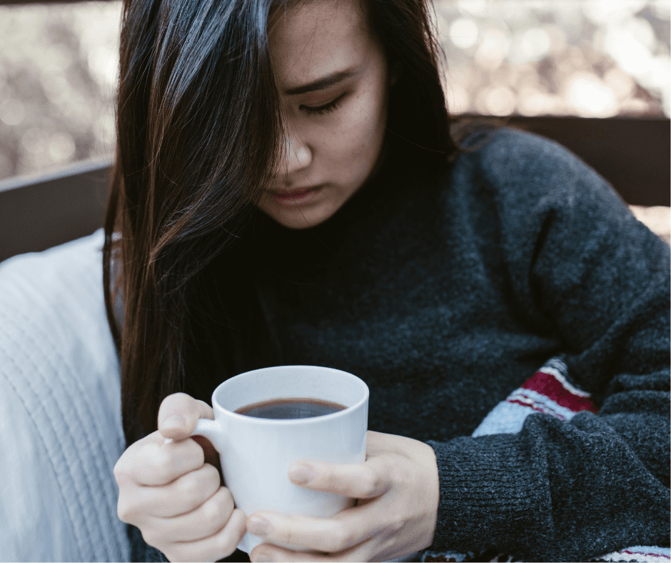 A young woman holding a cup of coffee worried