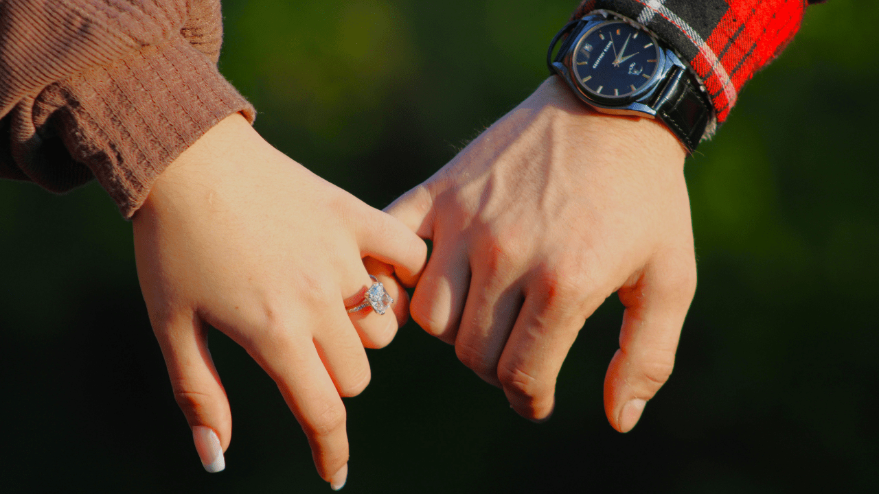 Close up of couple holding hands with engagement ring Close up of couple holding hands with engagement ring