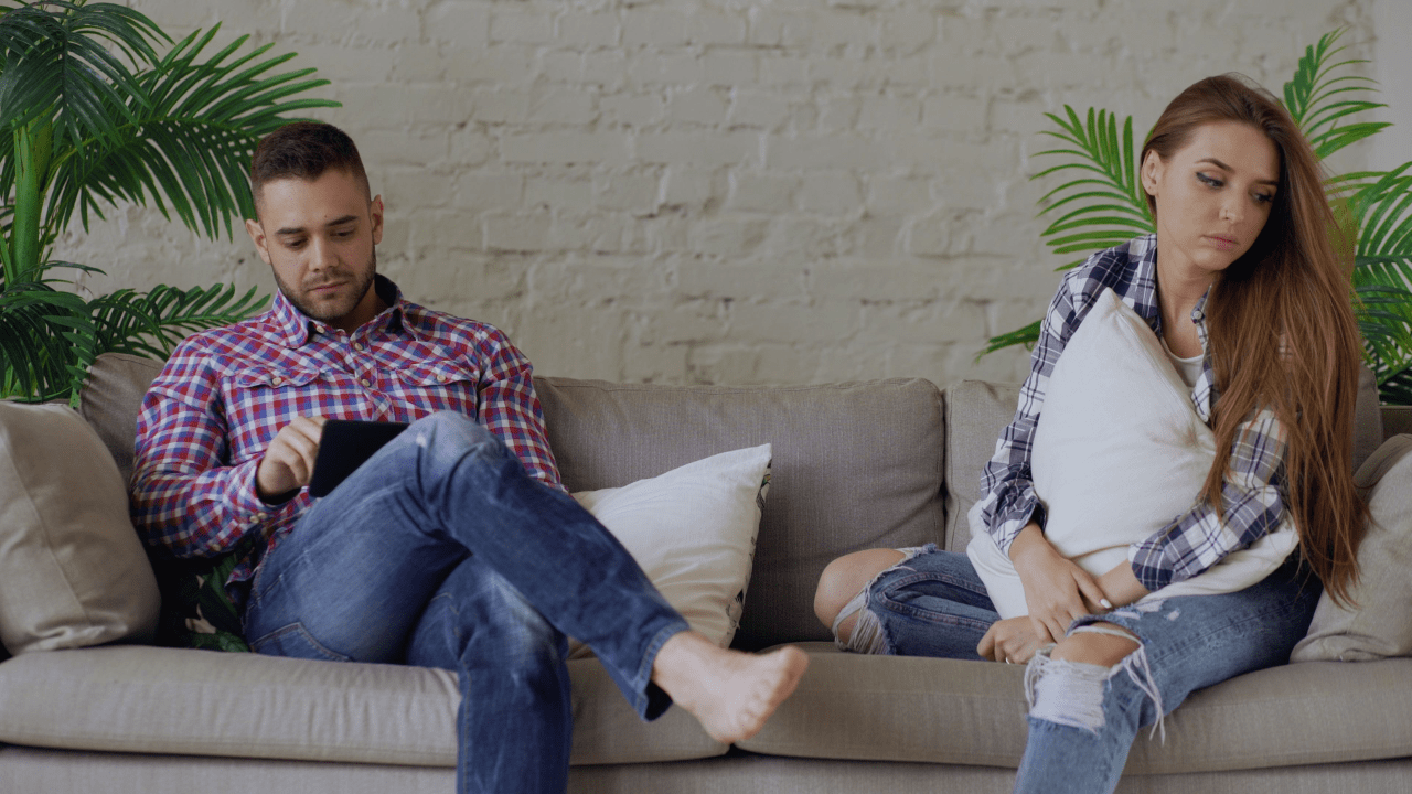 Man and woman sitting apart on a couch, illustrating relationship struggles and how couples therapy can help reconnect Man and woman sitting apart on a couch, illustrating relationship struggles and how couples therapy can help reconnect